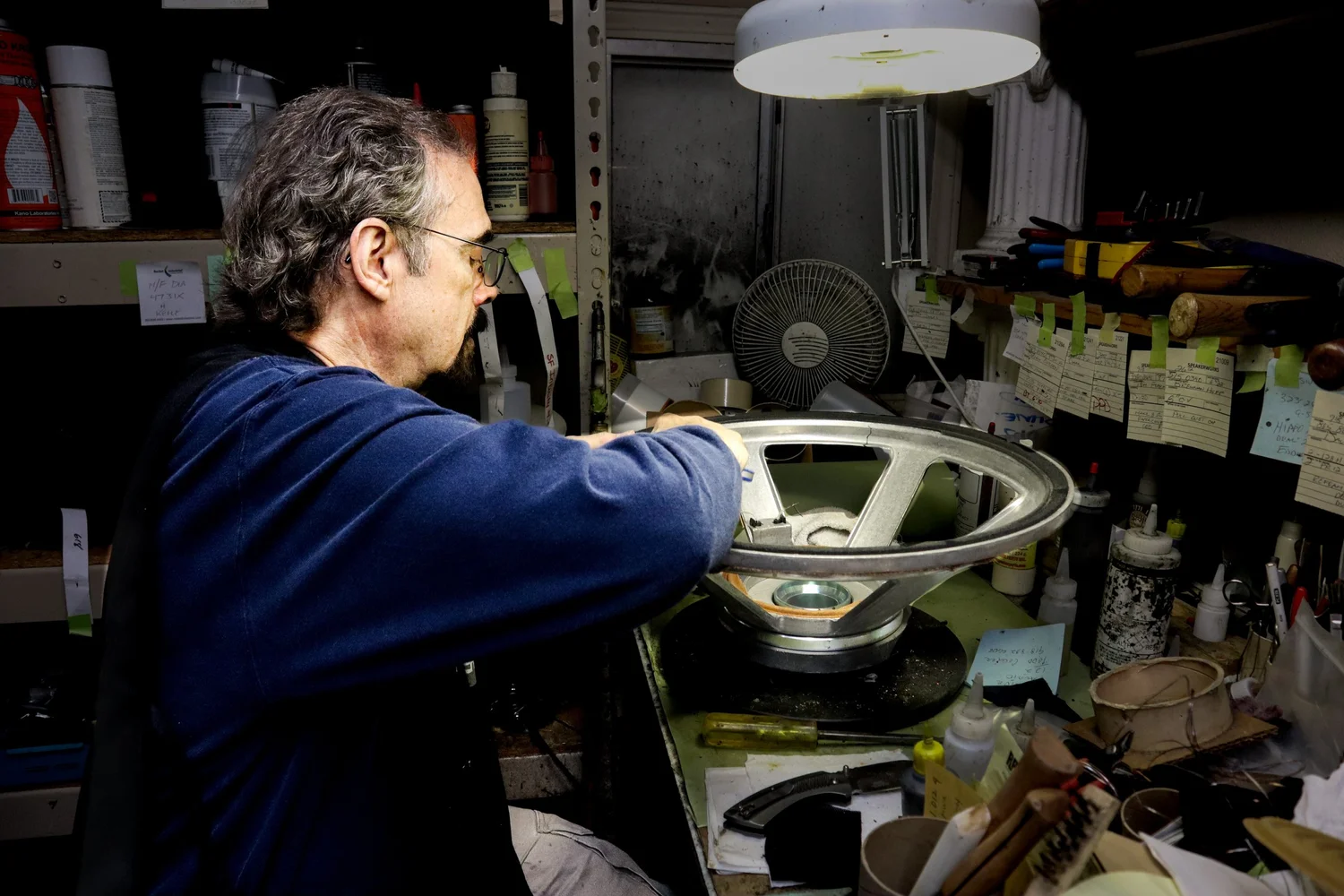 A technician working on a large speaker driver at the Speakerworks repair bench.